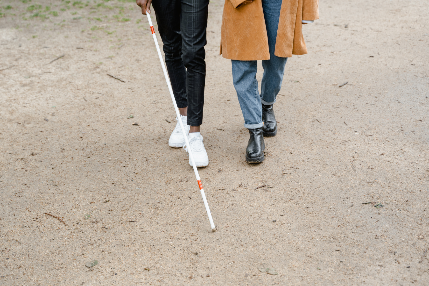 Person Walking with Another Person with White Cane